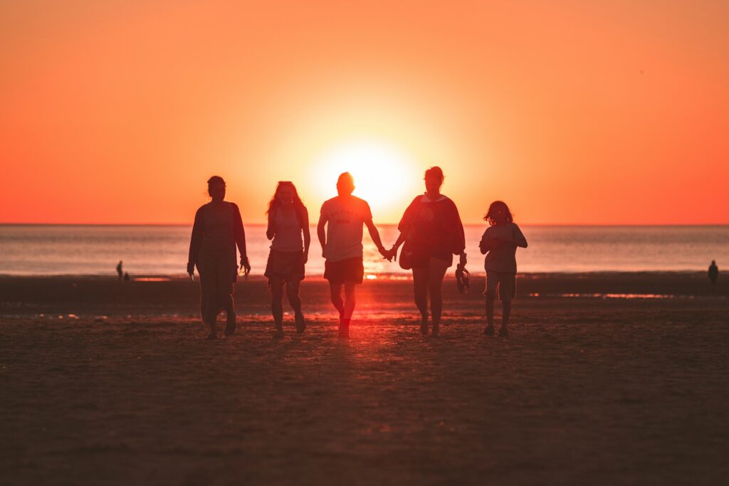 Three generations of a family walking together along the beach at sunset